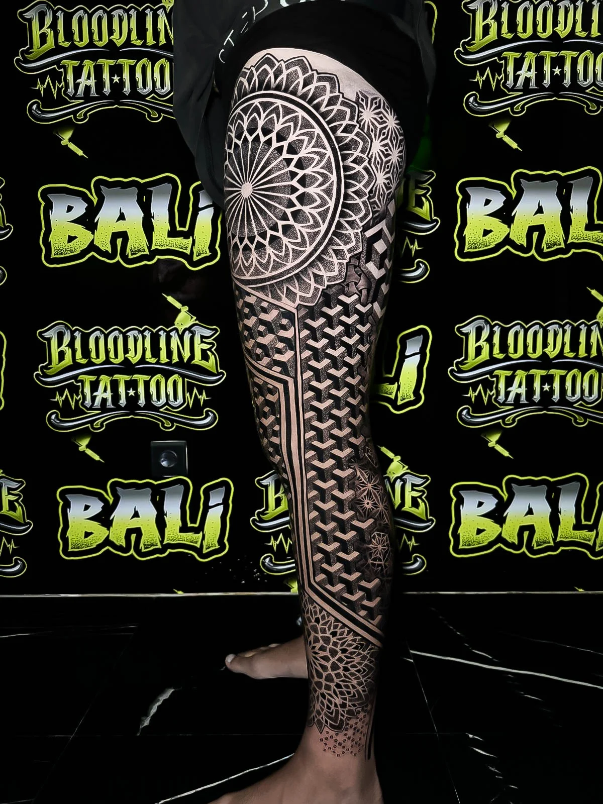 Side leg sacred geometry with a giant rosette mandala, stacked cube tessellation, and fine-dot shading through the calf panels at Bloodline Tattoo Bali.