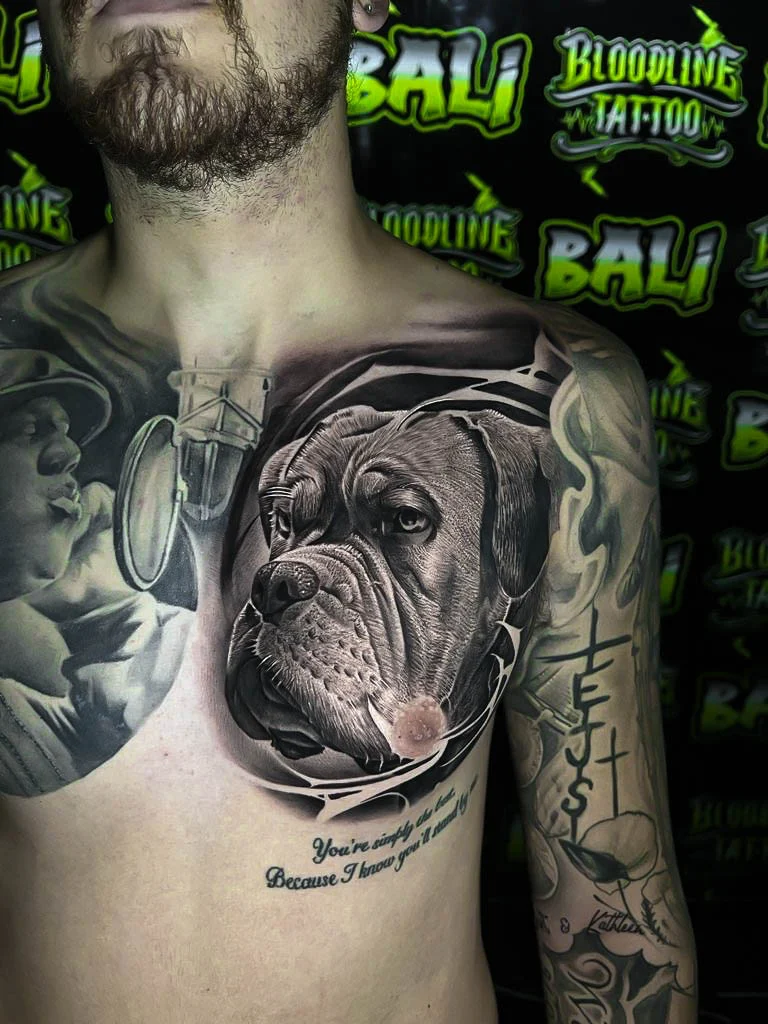 Black and grey portrait realism chest tattoo of a boxer dog portrait with smooth memorial shading and script below at Bloodline Tattoo Bali.